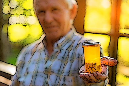 An older man holds his bottle of pills. 