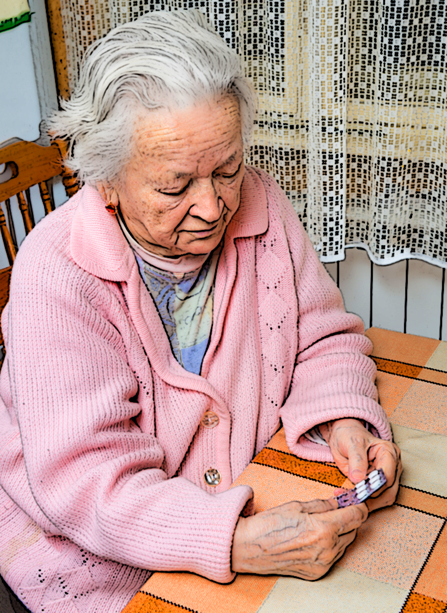 An older woman prepares to take some of the drugs she’s been prescribed. 