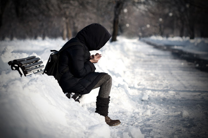 Winter time—person sitting on a bench in a snowy park