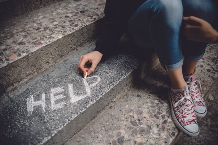 Girl drawing a help sign on the steps