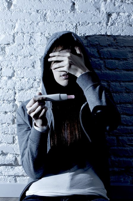 Young woman depressed, holding pregnancy test.