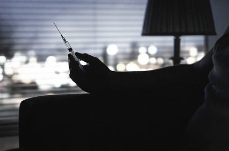 Addict holding syringe at home.