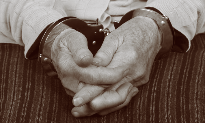 A senior citizen in handcuffs. 